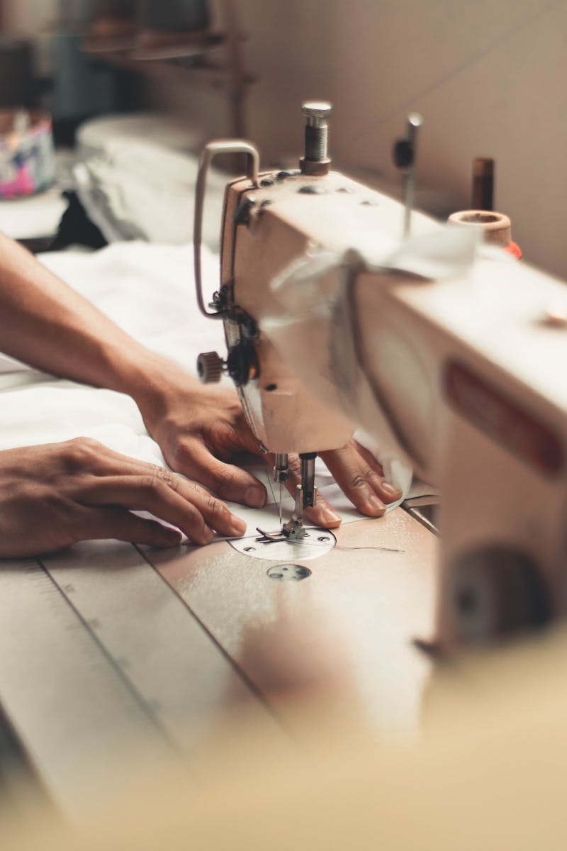 Taller Costura Aranzazu Pamplona - Close-up of hands using a sewing machine, depicting craftsmanship and textiles indoors.